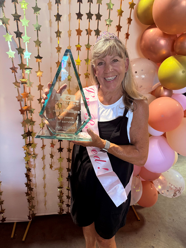 A photo of Jan at her retirement party, wearing a tiara and holding an award commemorating her 45 years of service at the company